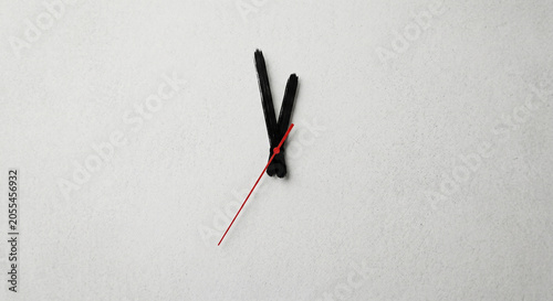 Abstract minimalist clock concept with brush stroke black hands on a textured white background