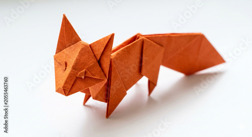 Origami Fox: A meticulously crafted origami fox, folded from vibrant orange paper, stands poised on a clean surface, showcasing the art of paper folding.