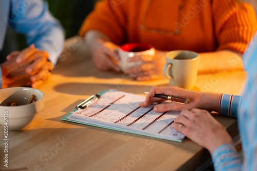 Photography Professional advisor filling out insurance paperwork during consultation with senior clients at home