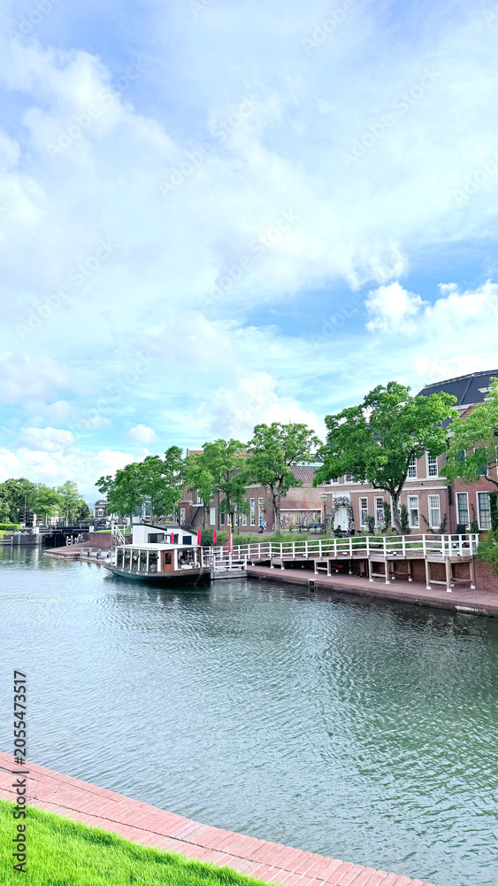 Fototapeta premium Scenic canal-side view with a boat and European-style brick buildings in Huis Ten Bosch, Japan