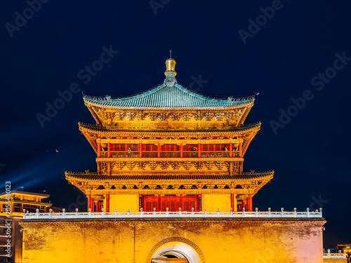 Illuminated ancient Bell Tower of Xian Shaanxi China glowing with golden lights under sky at night representing traditional Chinese architecture