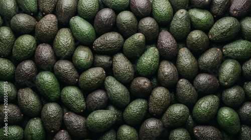 Fresh ripe avocado heap overhead view organic green fruit background
