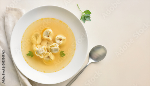 Tortellini in Golden Chicken Broth Served in White Bowl with Fresh Parsley Overhead Minimalist Food Photography