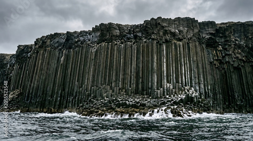 Geometric black basalt column cliffs rising vertically out of a stormy ocean sea