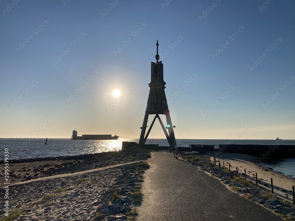 Fototapeta premium Kugelbake mit Schiff im Sonnenaufgang in Cuxhaven an der Nordsee