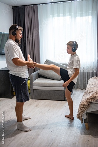 Father and son stretching together at home, enjoying a shared fitness moment.