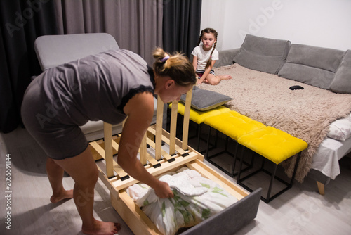 Woman assembling a pull-out bed while a child watches.