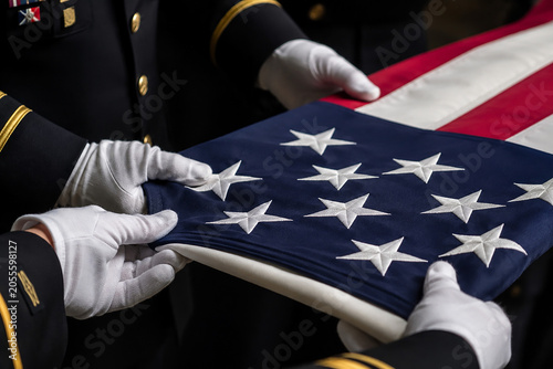 Bild auf Leinwand Military honor guard meticulously folds american flag with white gloved hands ceremony