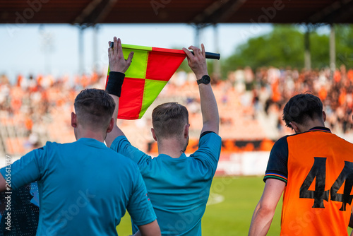 Foto Assistant referee holding a flag during a soccer match while officials and subst