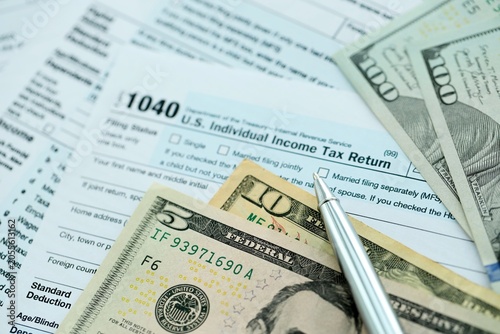 Bild auf Leinwand 1040 Individual Income tax return form and pen with dollars money bills on accou