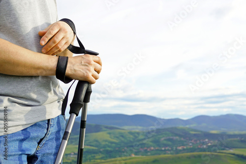 Fotografie Hands hold trekking poles against mountain landscape during hiking excursion