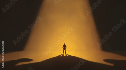 Lone businessman silhouette standing in golden spotlight with large shadow.