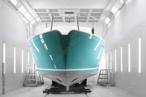Canvastavla Teal boat rests inside clean, bright paint booth