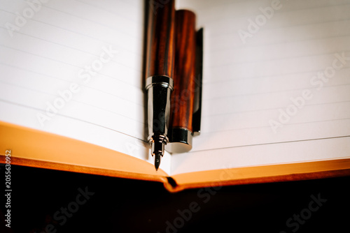 Wooden fountain pen rests on open lined notebook ready for writing