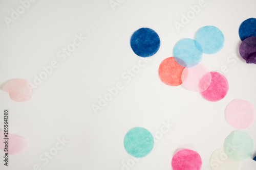Colorful paper confetti scattered along the edges of bright white background, creating playful and festive composition with abundant copy space. The image is ideal for celebration, party, and birthday
