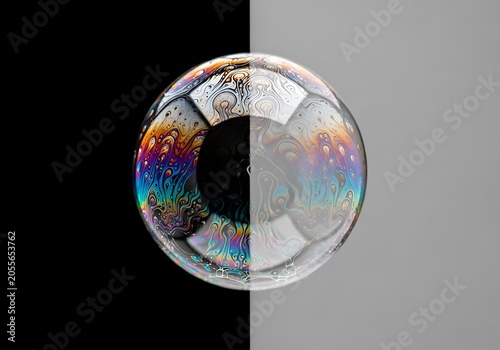 Close-up of a colorful soap bubble reflecting light against a split black and gray background