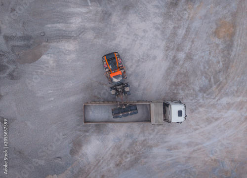 фотографія Top-down aerial view of an orange excavator loading crushed gypsum aggregate int