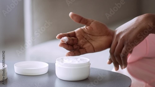 Focused Unrecognizable Black Female Applying Moisturizing Skin Cream With Finger At Home, Enjoying Daily Skincare Routine At Cozy Indoor Setting. Emphasizing Self-care And Wellness Concept.