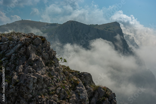 Majestic rocky mountain peak surrounded by thick white clouds and fog