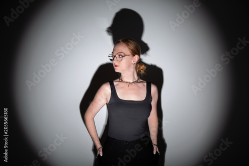 fotografia em estúdio, editorial de moda, modelo branca com cabelos ruivos longos, roupa preta, pose moderna com estética dramática iluminação focal com sombras marcadas