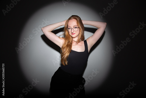 fotografia em estúdio, editorial de moda, modelo branca com cabelos ruivos longos, roupa preta, pose moderna com estética dramática iluminação focal com sombras marcadas
