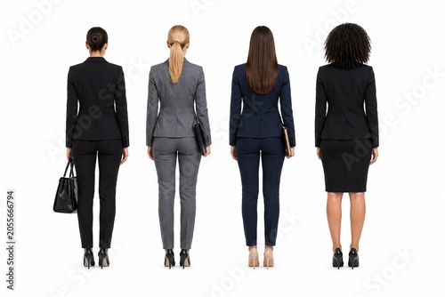 Rear view of four professional businesswomen in formal suits carrying handbags, isolated on a white background.