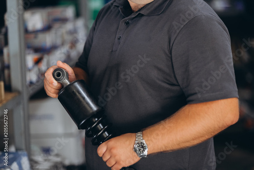 Quadro em tela Mechanic holding car shock absorber in workshop