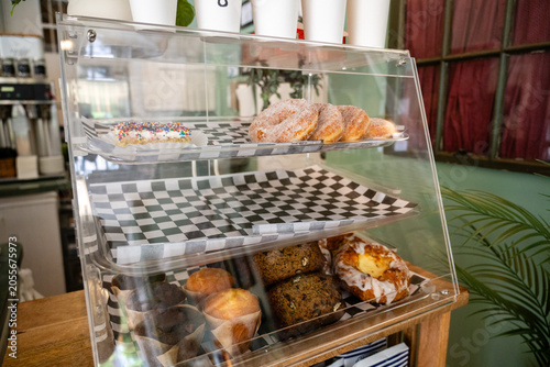 Close up of a glass display case filled with fresh pastries and baked goods inside a cafe.