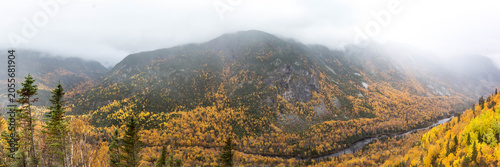 Misty mountain range covered in autumn foliage with a winding river in Charlevoix