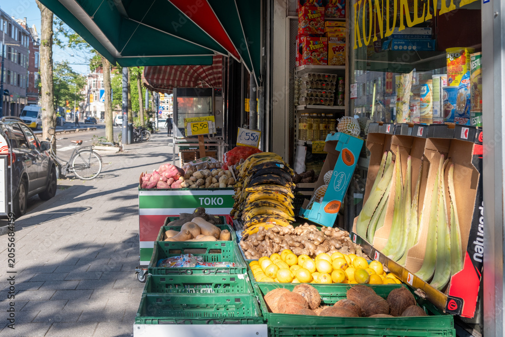 Obraz premium Produce display outside Amsterdam neighborhood toko on sunny urban sidewalk with tropical groceries