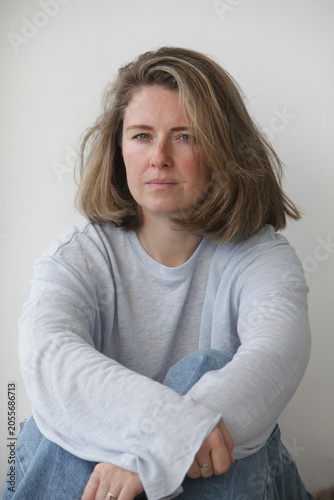 Fotografie Portrait of an authentic midlife woman with an sad, thoughtful expression indoors on neutral background