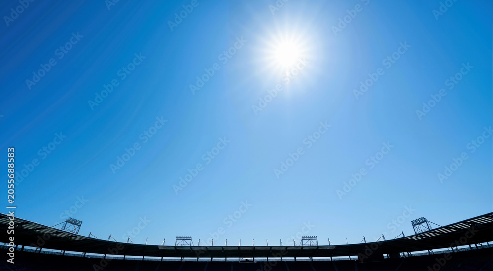 Fototapeta premium Bright sun in blue sky over stadium roof silhouette. Summer sports background with copy space