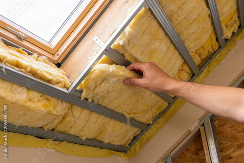 Tableau sur toile Homeowner installing yellow fiberglass insulation in attic ceiling for energy ef