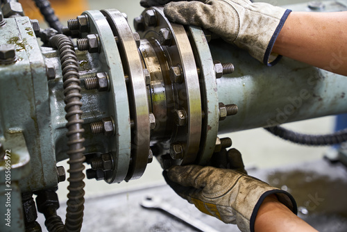Tableau sur toile Industrial worker in protective gloves tightening bolts on heavy machinery flang
