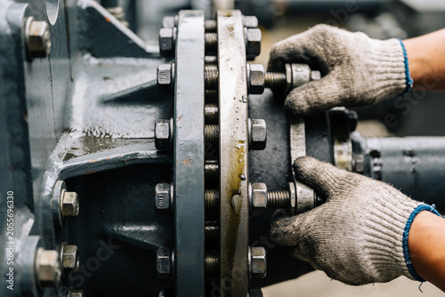 Obraz na plátně Mechanic tightening bolts on heavy industrial machinery with gloved hands