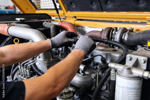 Fotografie Mechanic wearing gloves works on heavy machinery engine, focusing on turbocharge