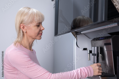 Morning beverage. Woman brewing fresh coffee using automatic coffee machine at home emphasizing lifestyle comfort and domestic moment