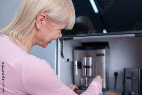 Morning beverage. Woman brewing fresh coffee using automatic coffee machine at home emphasizing lifestyle comfort and domestic moment