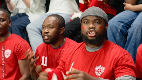 Photos Happy stadium crowd celebrating decisive winning goal during the final minutes of exciting football match, passionate fans cheering and jumping