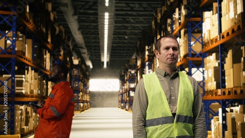 Foto Portrait of man depot worker in a logistics fulfillment center near racks, male wearing safety vest and handling packages for order fulfillment, global e-commerce and shipping operations