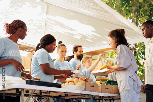 Photos Multicultural hunger relief team distribute free food to the needy providing assistance and support to homeless people, volunteers serving warm meals, aiming to alleviate hunger and poverty