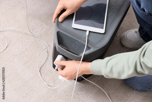фотографія Person plugging charger into portable power station with tablet charging on top,