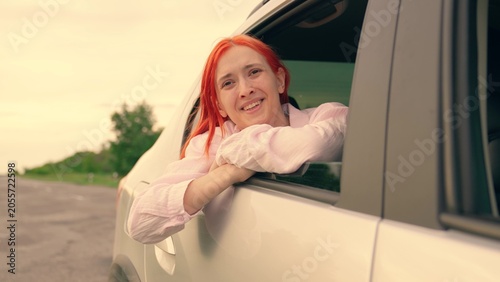 Canvas Print Young girl with red hair catches wind from car window