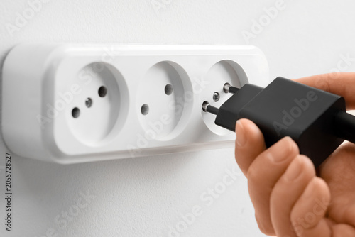 Hand plugging black charger...