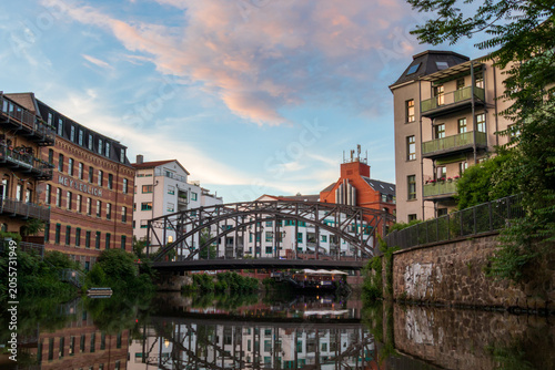 Weiße Elster canal with arched metal Könneritzbrücke and historic buildings at sunset in Leipzig from canoe view
