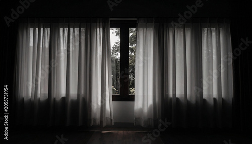 Open window with sheer white curtains gently moving in breeze