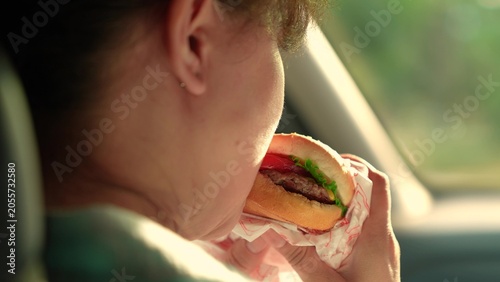 Принти на полотні Young woman satisfies hunger during car ride
