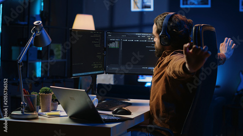 Quadro em tela Software programmer taking break from coding, putting headphones on and stretching on desk chair during remote job shift