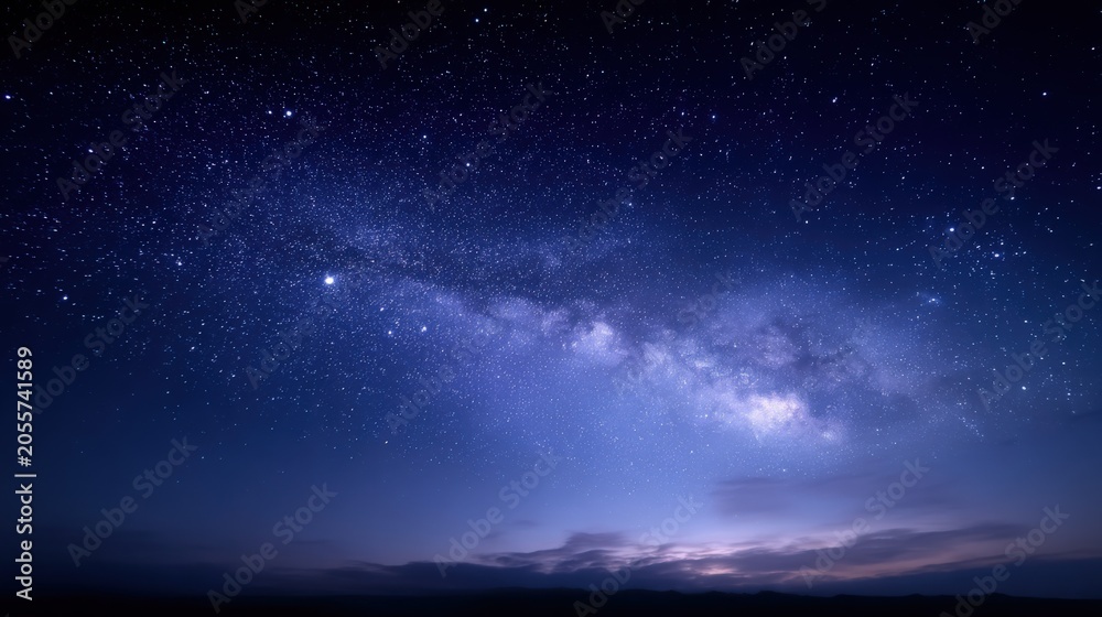 Fototapeta premium Vast Milky Way Galaxy stretching across the deep blue night sky filled with countless stars and faint clouds