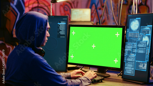 Foto Asian hacker in hidden place with graffiti walls using green screen computer to deploy malware on unsecured devices, stealing sensitive data from unaware users online and selling IT on black market